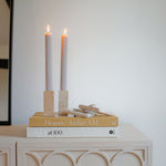 A chain of three handcrafted marble links  rests next to a pair of lit candles